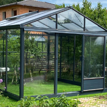 Modernes Gewächshaus aus Glas im Garten mit grüner Wiese und Pflanzen, Sommerstimmung. HANSEL.kraus metalltechnik gmbh