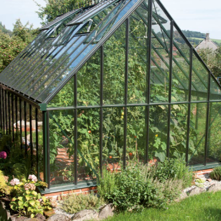 Ein großes Gewächshaus im Garten mit üppigen Pflanzen und grünem Rasen davor. HANSEL.kraus metalltechnik gmbh