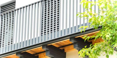 Moderner Balkon mit dunklem Geländer und Holzbalken, daneben grüner Baumast. HANSEL.kraus metalltechnik gmbh